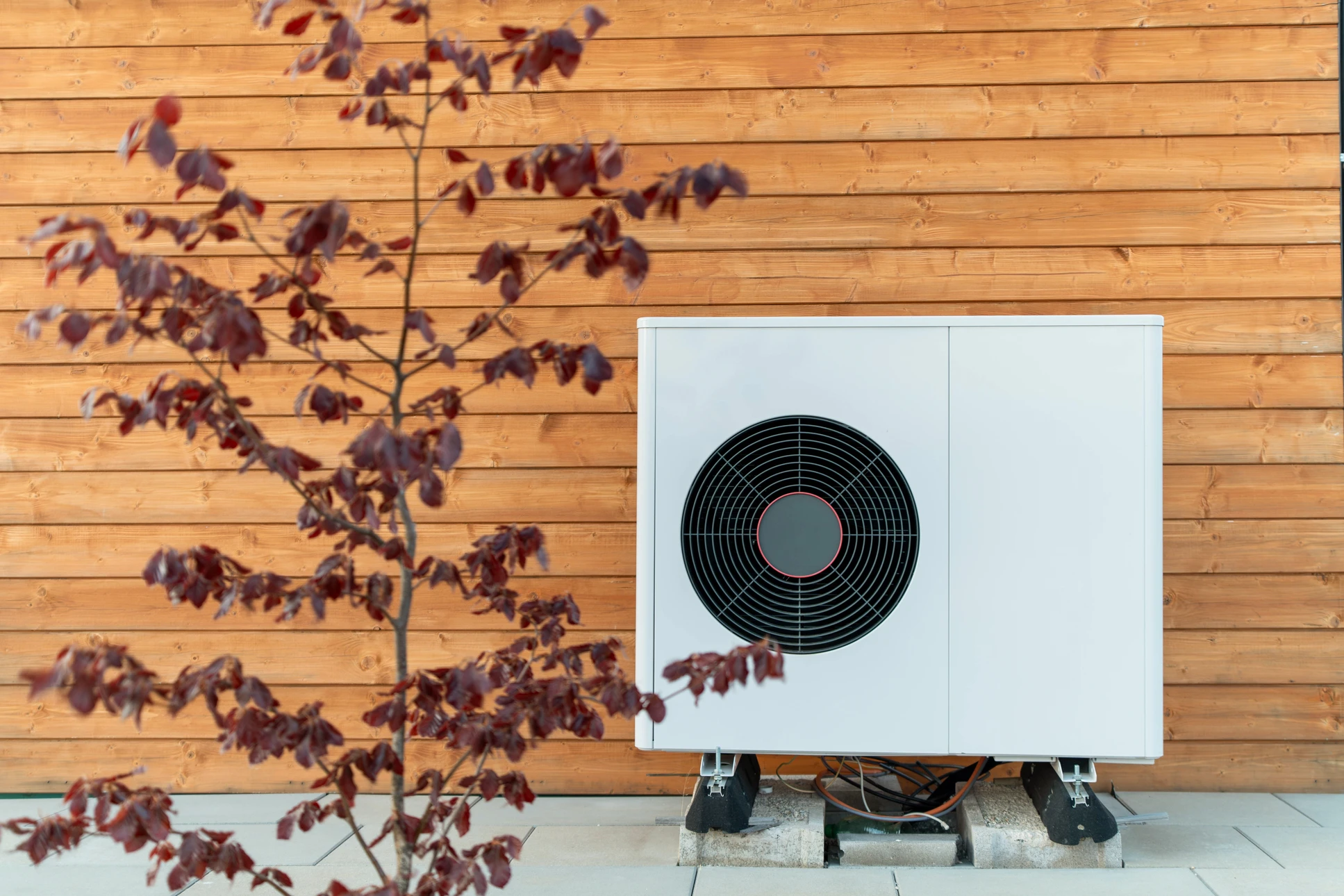 Extérieur résidentiel moderne avec pompe à chaleur air-eau installée sur socle béton contre façade blanche